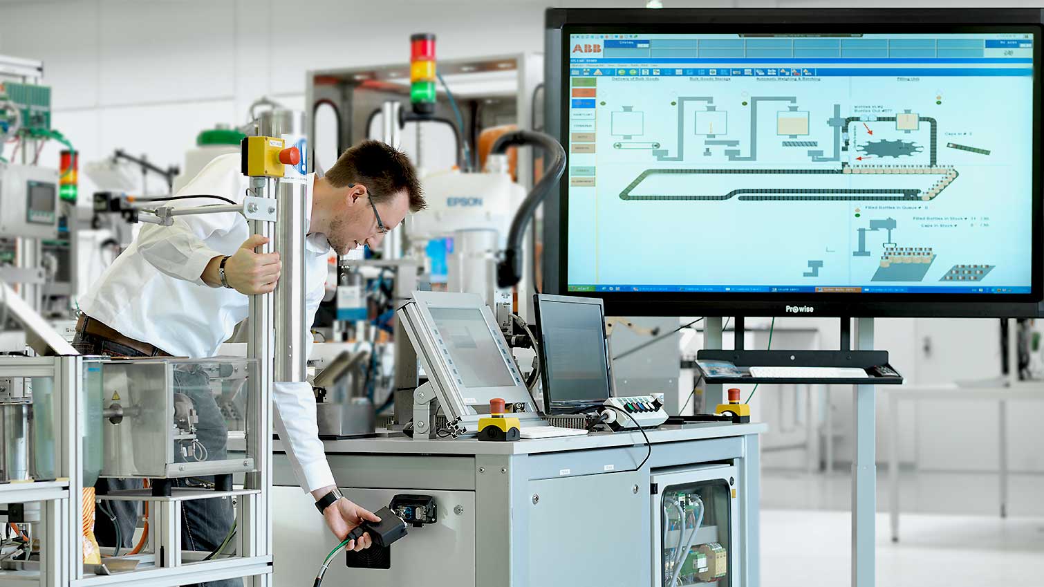 Spezialist arbeitet an einer industriellen Automatisierungsanlage mit Sicherheitsmonitor.
