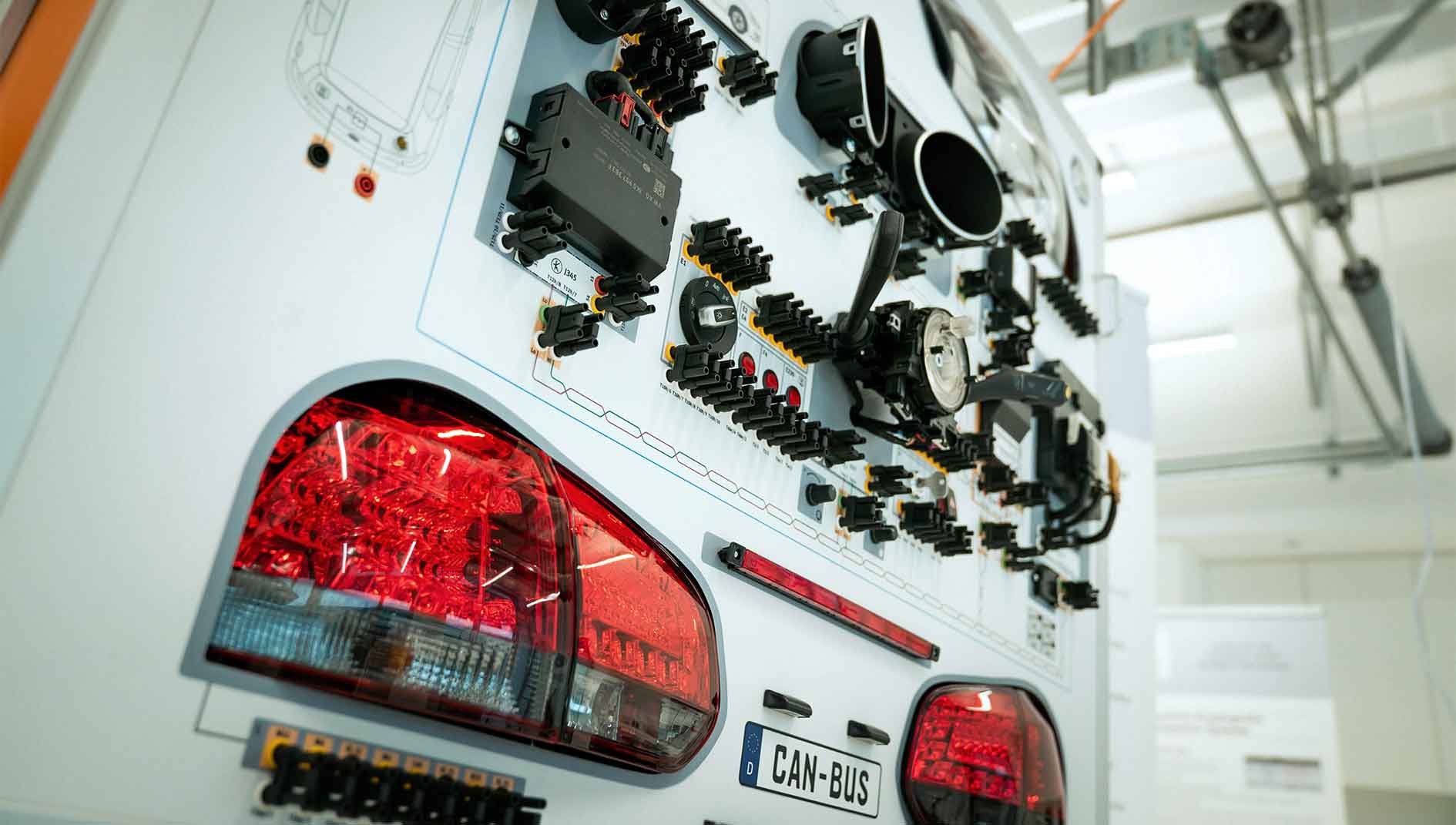 Fahrzeug-Heck mit CAN-Bus-Technologie-Demonstration: Rücklichter, Steuergeräte und Sensoren zeigen die Vernetzung moderner Fahrzeug-Elektronik. 