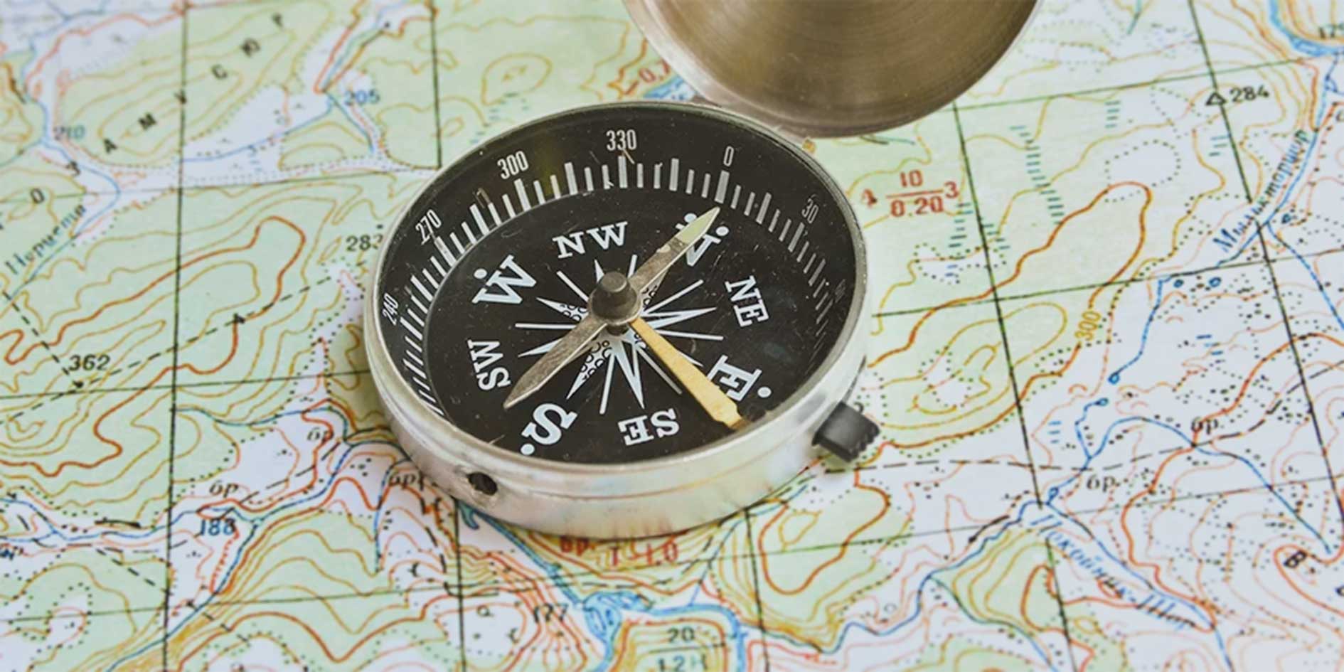 Kompass auf einer topografischen Karte als Symbol für Orientierung und sichere Navigation. Metapher für moderne und sichere Softwareentwicklung, strategische Planung und IT-Sicherheit.
