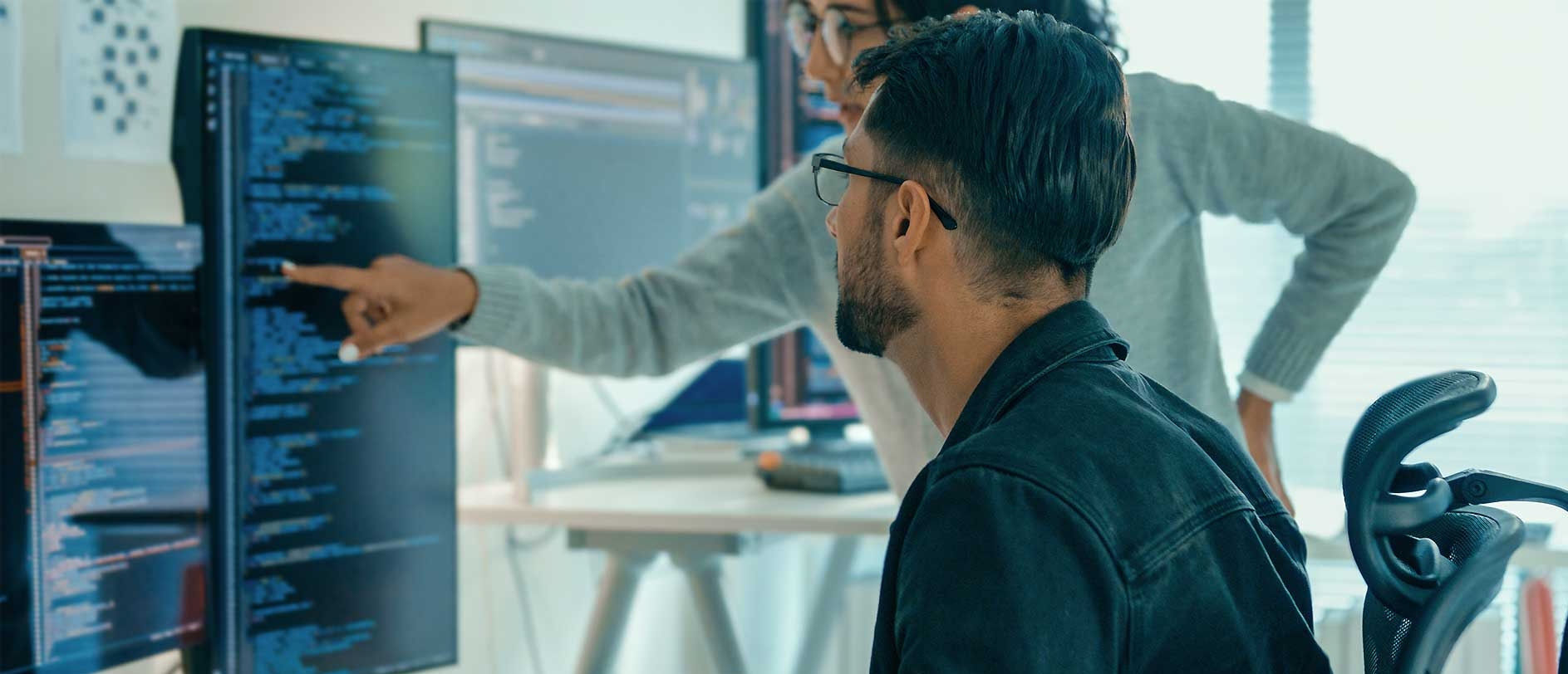IT-Fachkräfte analysieren gemeinsamen Quellcode auf einem Monitor.